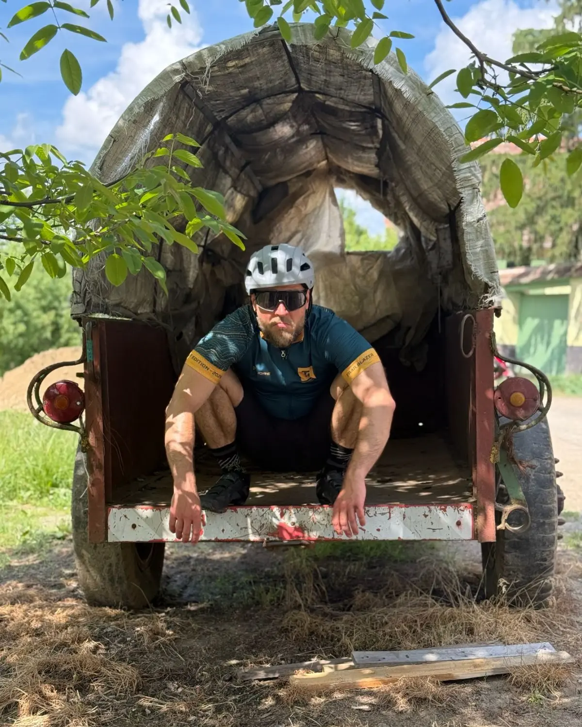 A rider crouched in the back of an old covered farm cart.