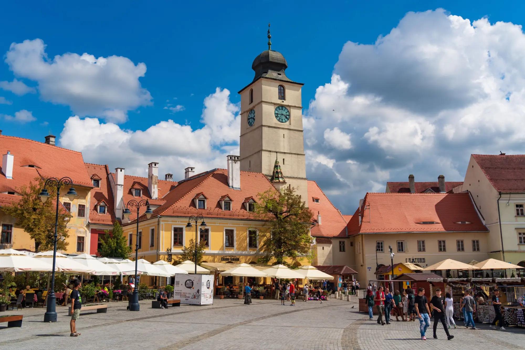 The Council Tower above the red roofs and café umbrellas of Piața Mare in Sibiu's old town.