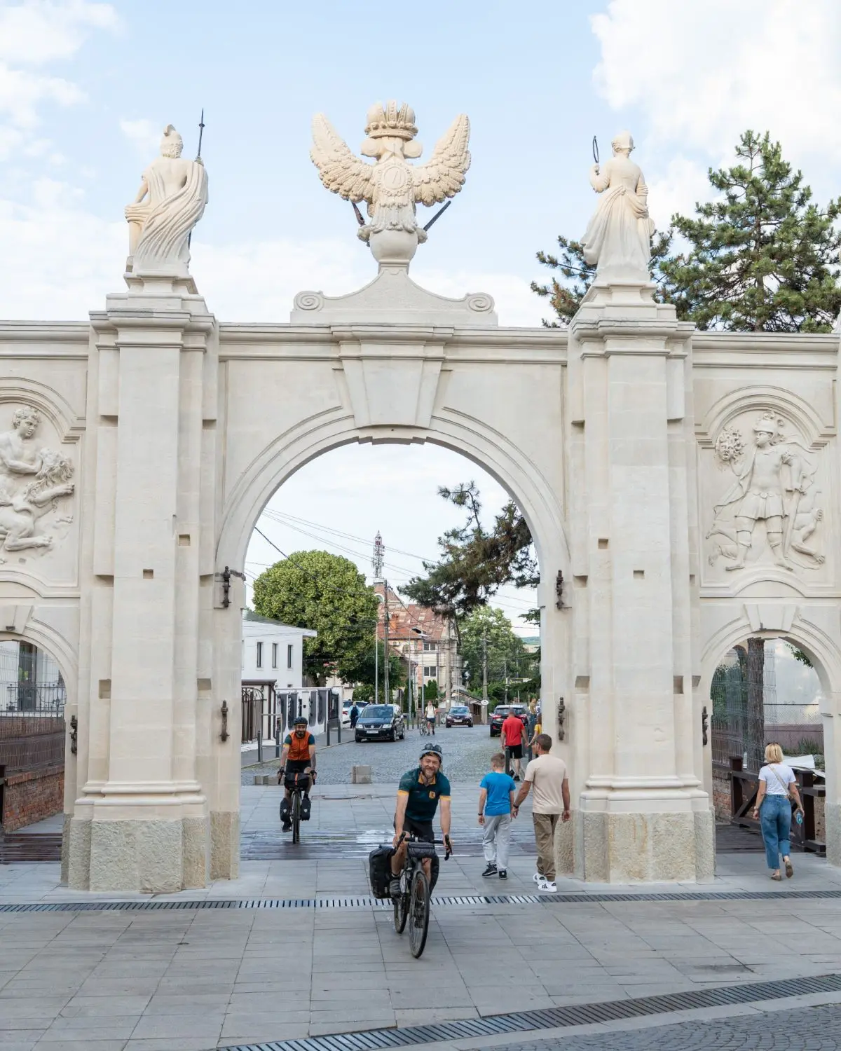 Two bikepackers riding through the baroque gate of Alba Iulia citadel.